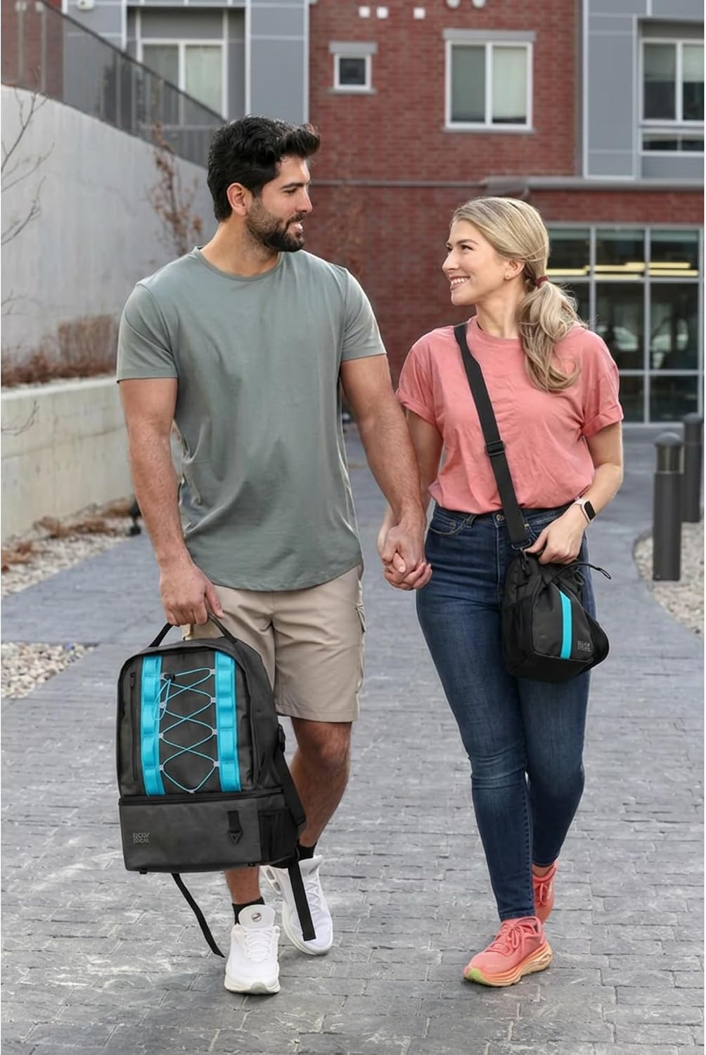 A couple walking together with the Red’s Way backpack and crossbody, both with blue stripes